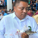 Man in white shirtholding a caiman
