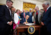 Trump signs a bill surrounded by supporters
