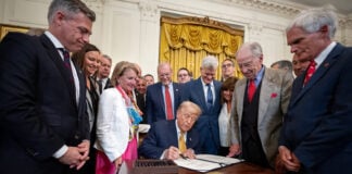 Trump signs a bill surrounded by supporters