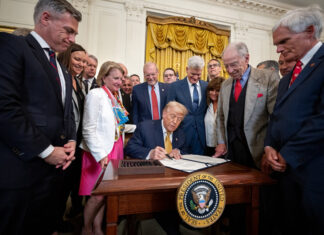Trump signs a bill surrounded by supporters