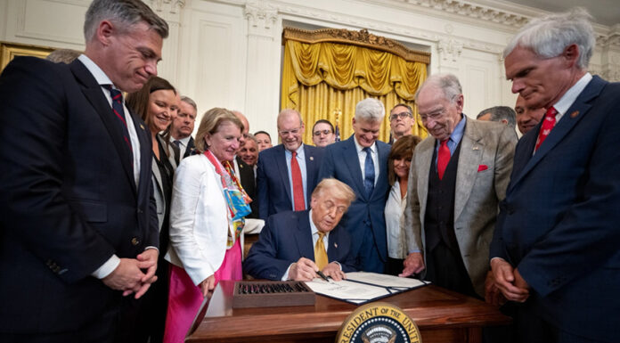 Trump signs a bill surrounded by supporters