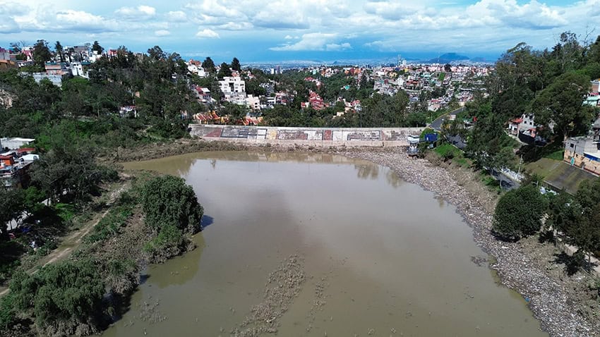 A dam surrounded by trees with a city in the background