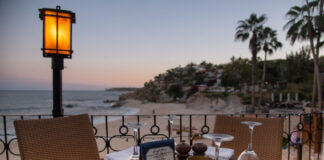 A reserved table at an outdoor restaurant overlooks a beach and ocean at sunset in Los Cabos, Baja California Sur, Mexico