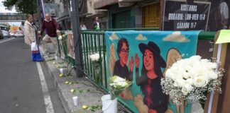 A streetside altar in Mexico City with flowers and a banner honoring two aides to Mayor Clara Brugada who were killed in May