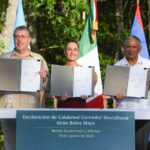 Three heads of state at a podium holding papers