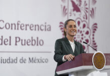 President Sheinbaum smiles from behind a podium next to a banner reading "Conferencia del Pueblo"