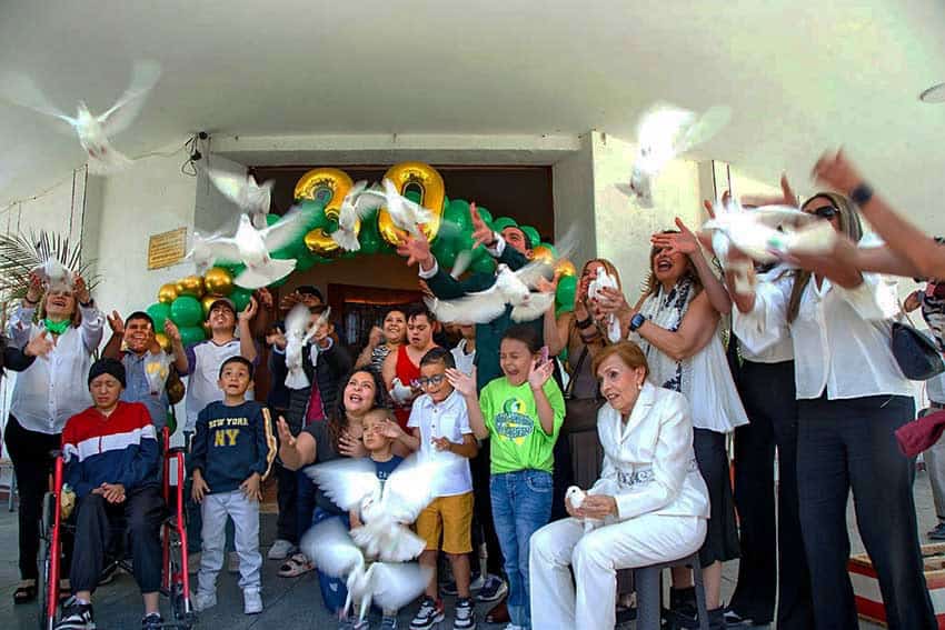 A group of adults and children posing in front of a large display. The number 30 is written with balloons
