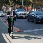 two men in suits riding electric scooters