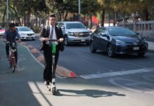 two men in suits riding electric scooters