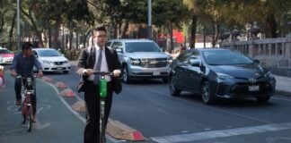 two men in suits riding electric scooters