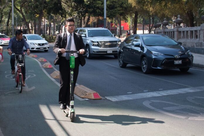 two men in suits riding electric scooters