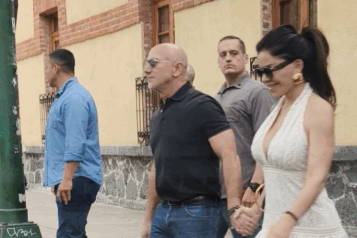 Jeff Bezos and Lauren Sanchez hold hands while walking in a paparazzi photo