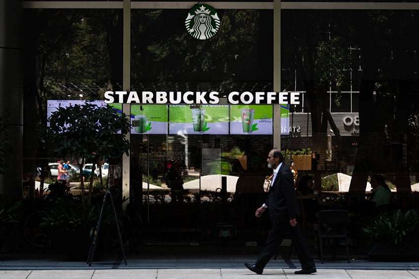 A man in a suit walks past a Starbucks coffee shop in Mexico City