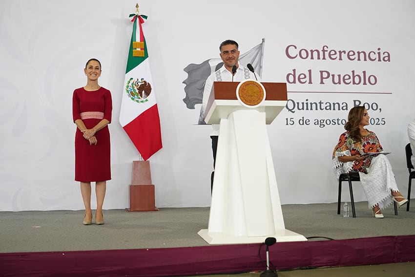 Federal Security Minister Omar García Harfuch smiles behind a podium as Sheinbaum and other politicians look on