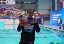 swimmer showing medal by a pool