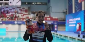swimmer showing medal by a pool