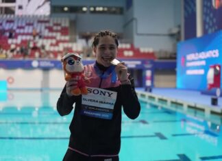 swimmer showing medal by a pool