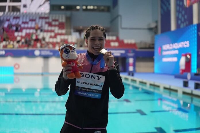 swimmer showing medal by a pool