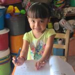 A young girl writing in a textbook