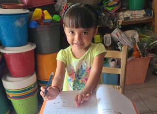 A young girl writing in a textbook