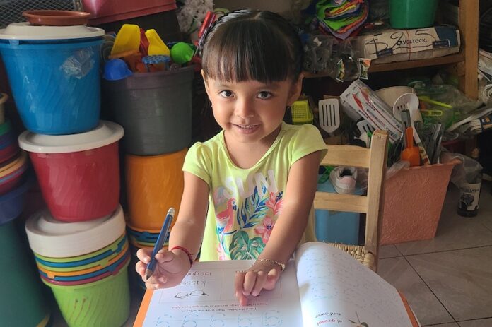 A young girl writing in a textbook