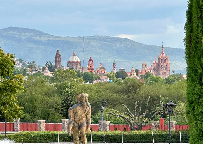 The San Miguel de Allende skyline visible behind a green park full of trees