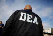 A bald white man in a DEA jacket