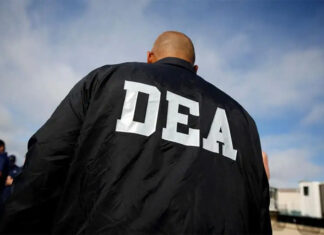 A bald white man in a DEA jacket