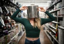 A woman with a pan on her head standing in a supermaret aisle