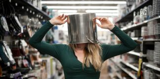 A woman with a pan on her head standing in a supermaret aisle