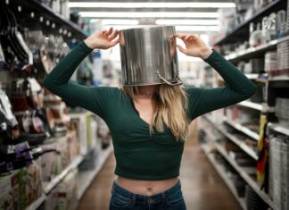 A woman with a pan on her head standing in a supermaret aisle