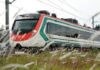 A red, white and green train speeds through a field.