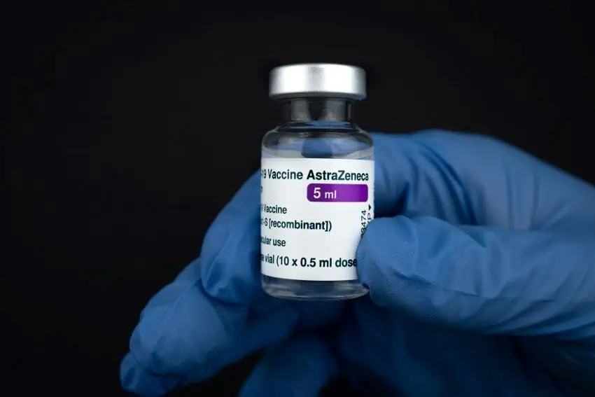 A gloved hand holds up a COVID vaccine made by pharmaceutical company AstraZeneca