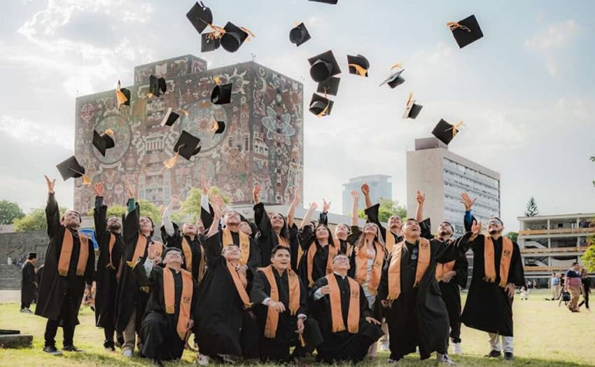 College graduates show their caps in celebration outside the colorful mosaic-covered UNAM Central Library in Mexico City