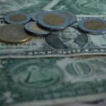 peso coins on top of dollar bills