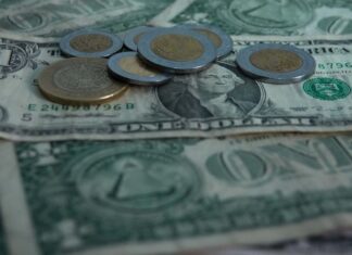 peso coins on top of dollar bills