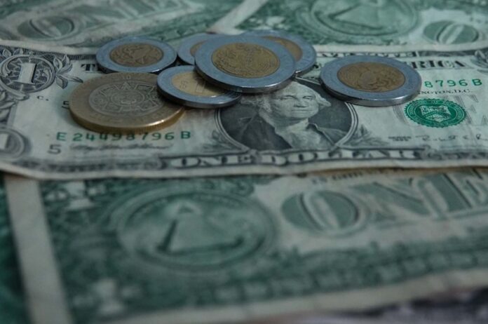 peso coins on top of dollar bills