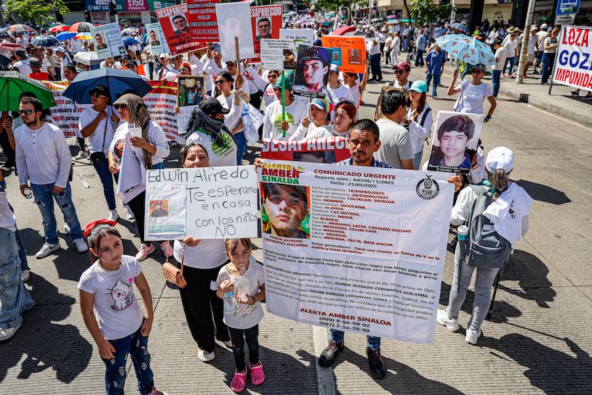 Peace march participants hold up a large disappearance notice along with a sign that says, "Edwin Alfredo, we're waiting for you to come home. Not with the kids!"