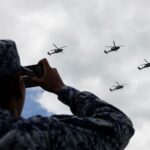A soldier records the passage of Armed Forces helicopters during rehearsals for the Military Air Parade marking the 215th anniversary of the start of the Mexican War of Independence