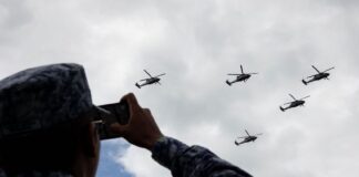 A soldier records the passage of Armed Forces helicopters during rehearsals for the Military Air Parade marking the 215th anniversary of the start of the Mexican War of Independence
