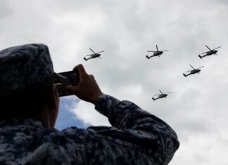 A soldier records the passage of Armed Forces helicopters during rehearsals for the Military Air Parade marking the 215th anniversary of the start of the Mexican War of Independence