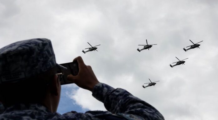 A soldier records the passage of Armed Forces helicopters during rehearsals for the Military Air Parade marking the 215th anniversary of the start of the Mexican War of Independence