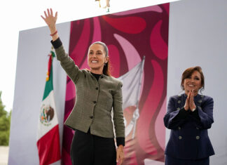 President Claudia Sheinbaum smiles and waves to a crowd from a stage