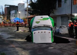 Jarritos truck sticks out from a sinkhole on a street in Mexico City