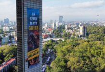 Greenpeace banner hanging from Estela de Luz that says "La Selva Maya Grita!"