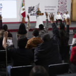 Reporters in the press pool raise their hands at President Sheinbaum's morning press conference