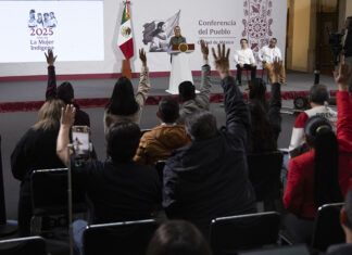 Reporters in the press pool raise their hands at President Sheinbaum's morning press conference