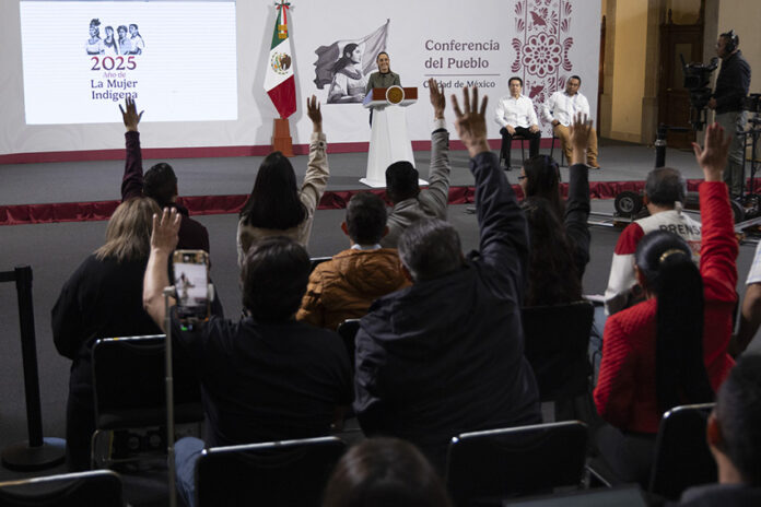 Reporters in the press pool raise their hands at President Sheinbaum's morning press conference