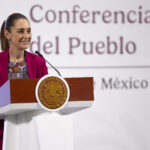 "Conferencia del Pueblo" reads a banner behind President Sheinbaum as she stands at the podium of her morning press conference