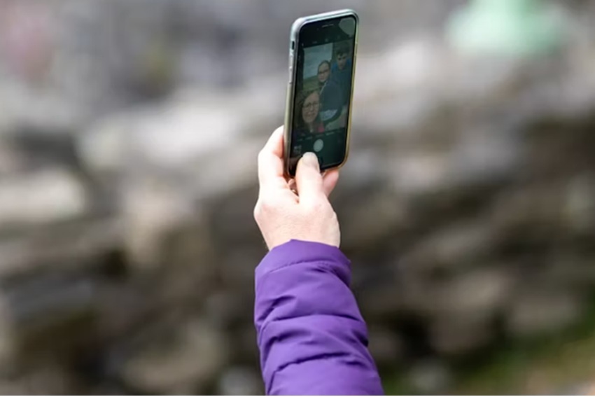 Female arm in purple coat and hand holding mobile phone chat 
